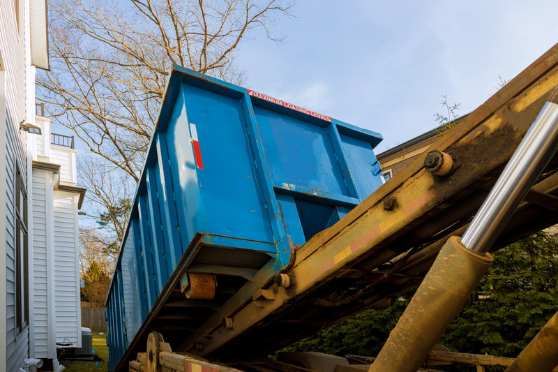 Blue dumpster is being placed next to a home in Kenosha county as they begin their rental with us.