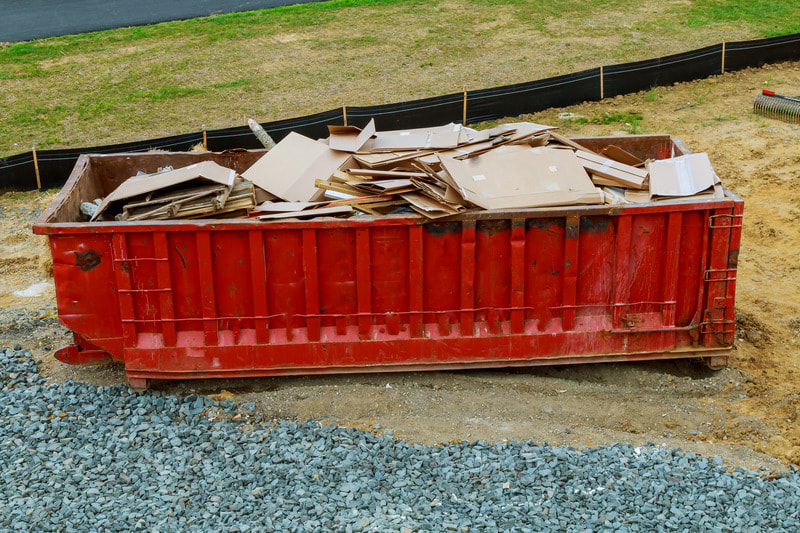 Red dumpster is full of cardboard and other materials, ready to be taken off the property.